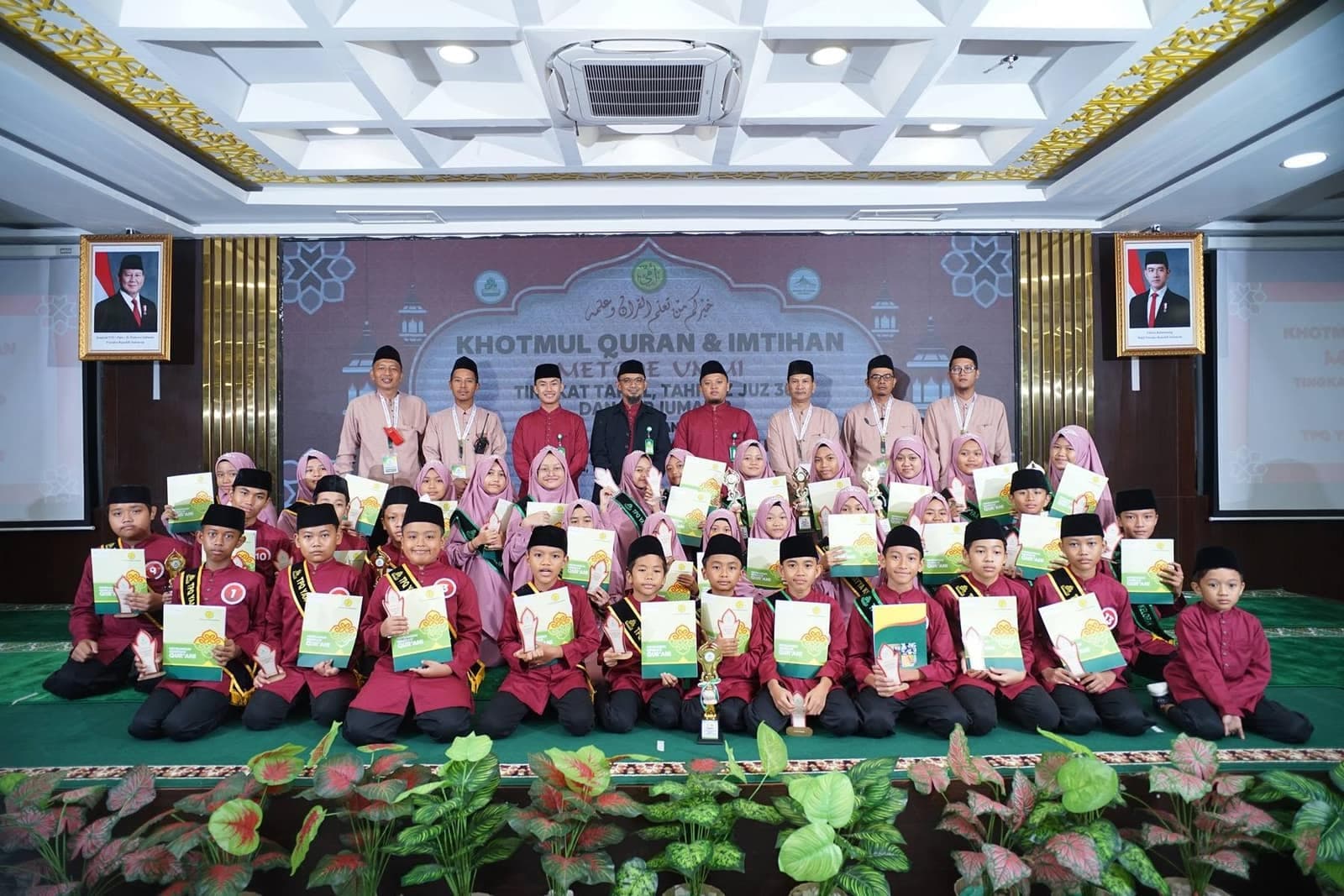 Wisudawan berseragam merah berfoto bersama dengan piala